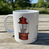 White ceramic coffee mug with a retro illustration of a red Coleman 200A lantern. Old Coleman Parts logo visible.